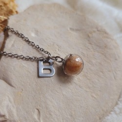 Collier souvenir réalisé avec une sphère en verre remplie de poils d'animaux, de plumes, de mèches de cheveux ou de crins.