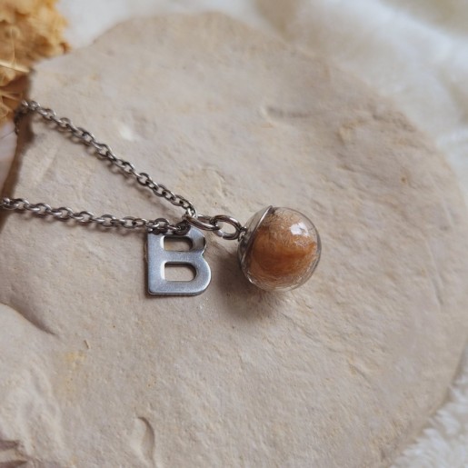 Collier souvenir réalisé avec une sphère en verre remplie de poils d'animaux, de plumes, de mèches de cheveux ou de crins.