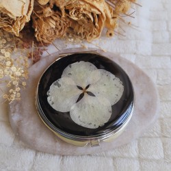 Miroir de poche rond agrémenté d'une fleur séchée d'Hortensia blanc.