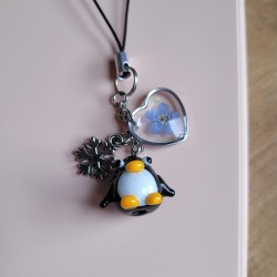 Bijoux de téléphone spécial Noël avec pendentif Pingouin en verre et fleurs séchées de Myosotis.