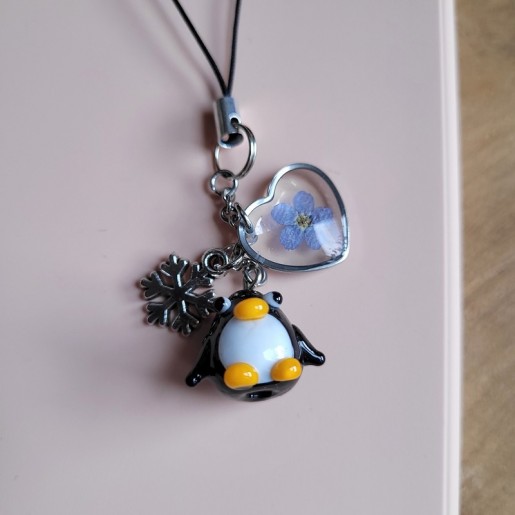 Bijoux de téléphone spécial Noël avec pendentif Pingouin en verre et fleurs séchées de Myosotis.