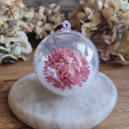 Boule de Noël en plastique avec fleur séchée d'Immortelle rose et fausse neige.