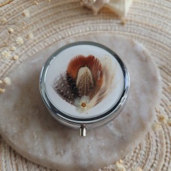 Pilulier rond en métal argenté, résine et plumes naturelles. Pilulier 3 compartiments.