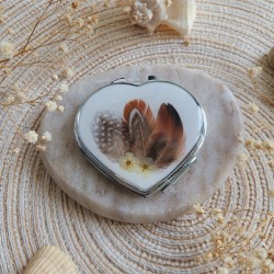 Miroir de poche coeur en métal argenté agrémenté de plumes naturelles.